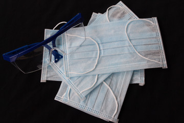 Close up shot of medical accessories on warm background. Plastic glasses and face mask supply during corona virus outbreak in Europe. Covid-19 concept, international crisis.