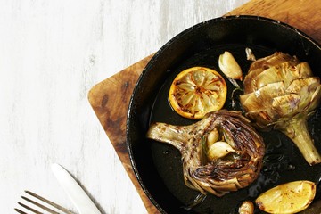 grilled artichoke with lemon in a pan.  Flatlay.  copy space. top view