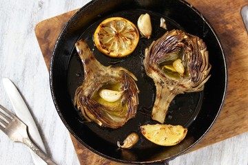 grilled artichoke with lemon in a pan.  Flatlay.  copy space. top view