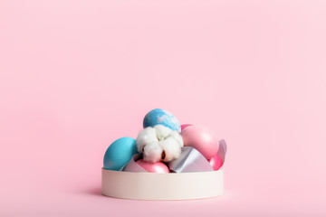 Still life with easter decorated eggs in a box on a pink background.