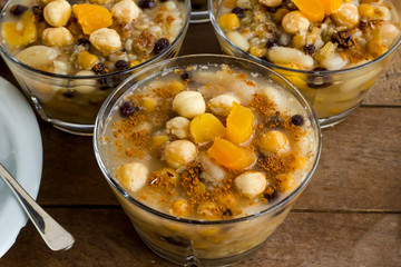 Traditional Dessert Asure,Noah Pudding or Ashura designed in stylish glass bowls on wooden table.Chopped apricot and hazelnuts topping.Conceptual image of Asure Day.