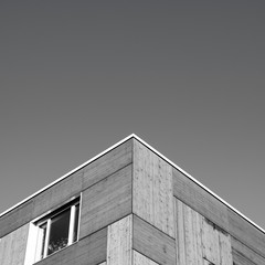 An abstract black and white image of a geometrical roof of a building and a window