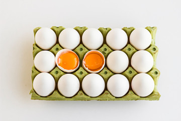 Fifteen fresh,white eggs in carton box,two eggs broken of fifteen.Top view,flat layout.