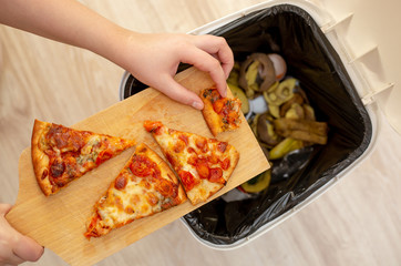 Woman hands throwing food into the trash, bin, waste of food, food concept