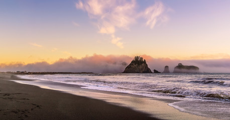 Fototapeta na wymiar Rialto Beach at dusk with sea stacks covered with clouds coming from the ocean, Olympic National Park, Washington state, USA.