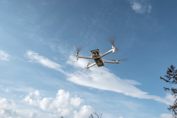 White quadrocopter drone with camera hangs in the air on the background of beautiful nature in winter