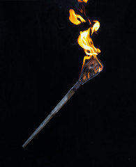 wooden burning torch on a black background - obrazy, fototapety, plakaty