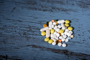 Different colored medications and tablets on blue texture background. Concept of Health Care. Copy space.