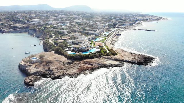 Sarantaris cape at Crete, many resorts at sea side, aerial panorama. Rocky headland washed by water, flat sandy beaches on right, rough coast
