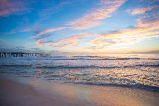 panama city beach florida ocean at shoreline with beautiul sunset clouds and pier into the water