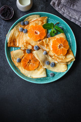 crepes with citrus, jam and berries (thin pancakes, mandarin, blueberry) menu concept. background. top view. copy space for text