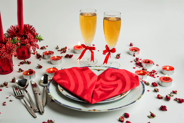 A romantic table setting with stylish and elegance dining ware, red candles and decorative roses.Selected champagne glasses as focus 