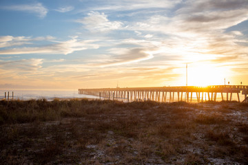 panama city beach florida ocean at shoreline with beautiul sunset clouds and pier into the water