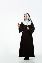 beautiful young happy nun standing on white