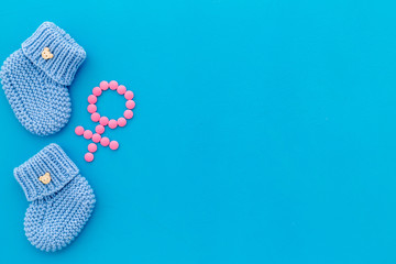 Baby booties for girl - pregnancy concept with Venus sign - on blue background top-down copy space