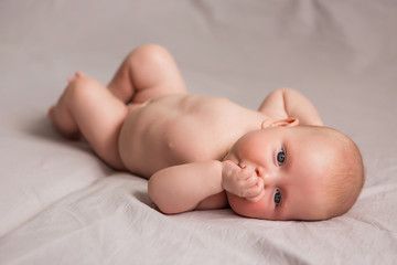 Happy 3 months old baby smiling, lying on white bed