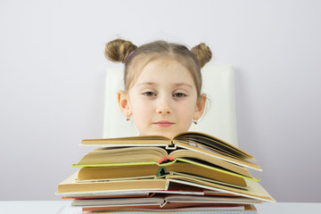 beautiful Caucasian little girl with a stack of books, education concept