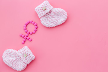 Pink booties for girl - pregnancy concept with Venus sign - on pink background top-down copy space