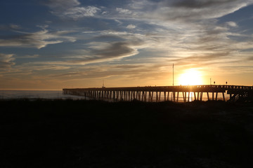 sundown at panama city beach pier with silhouette beach and pier and sunset clouds and sky