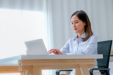 Pretty business Asian girl work at home with laptop in the bedroom with day light.