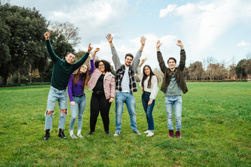 Group of teenagers of different cultures with your hands raised towards the sky at the park - Teamwork of young people - Six men and women having fun together