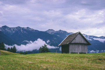 Fototapeta na wymiar View over Slovenian Alps, landscape with hay sheds, paths, trees and clouds