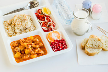 Traditional Turkish Meal with chicken potato,rice,tomato salad and fruits in the white portion food tray.Table d'hote-known TABLDOT in TR-Designed on the white surface.