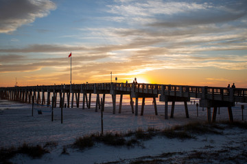 Fototapeta na wymiar sunset at panama city beach pier with sun going down behind pier and beautiful clouds and sky and ocean