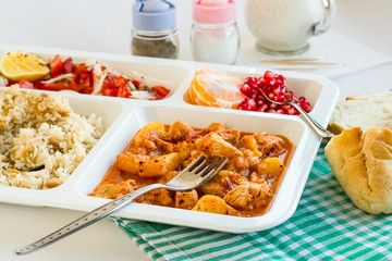 Traditional Turkish Meal with chicken potato,rice,tomato salad and fruits in the white portion food tray.Table d'hote-known TABLDOT in TR-Designed on the white surface.