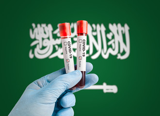 Pandemic COVID-19 concept: Scientist holding blood sample in test tubes with positive test result marked in front of Saudi Arabia flag.