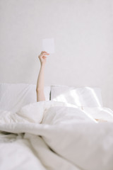 Girl in bed holding a card. Vertical concept photo