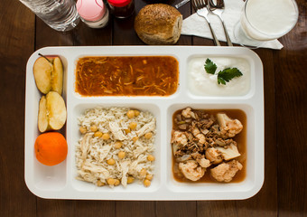 White food tray (table d'hote) with traditional Turkish meals and a bottle of water on wooden...