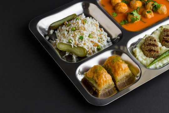 Traditional Turkish meals,meatballs soup,rice,mashed potatoes,grilled meatball and two slices of baklava in stainless steel food tray.Table d'hote(known Tabldot in Turkey) top view.