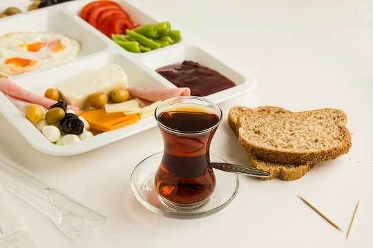 Traditional Turkish breakfast with cheese, salami, pepper, jam, egg, tomato and olives in a plastic white food tray (table d'hote) on white 
