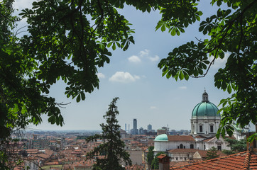 View from the top of the hill on the Dome of the Cathedral of Santa Maria Assunta and skyscrapers in the business part of the city . Brescia. Italy. Soft focus, blurry background.