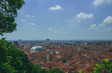 The dome of the Comune di Brescia against the background of tiled roofs, in the haze of a hot day. Brescia, Italy. Soft focus, blurry background.