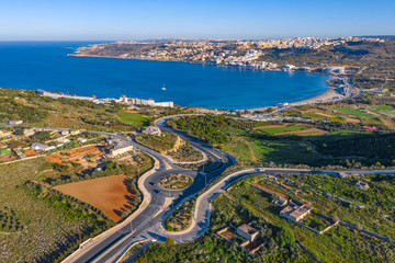 Aerial landscape view of roundabout, bay, beach and Mediterranean sea. Mellieha city. Europe. Malta island
