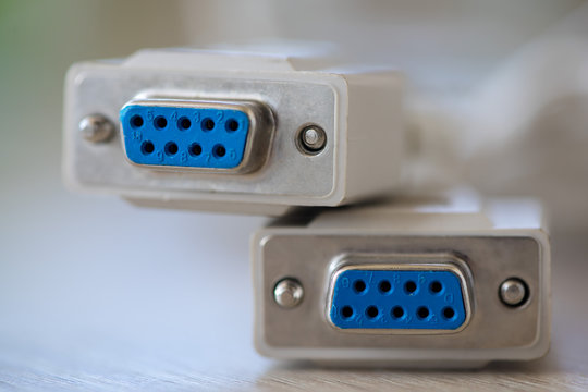 Close-up of a RS-232 serial port. Female to female extension cord on a wooden table.