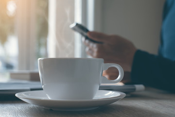 Cup of black coffee and  man using smartphone