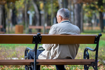 Fototapeta premium Man sitting on a bench in a park. Real people.