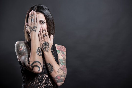 Ragazza tatuata morasi portale mani in faccia , isolata su sfondo nero