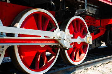 Red driving wheels of a vintage steam engine locomotive. Driving rods, drives, cranks and other parts. The history of railway transport.