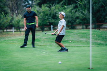 Fototapeta premium Golf Putting Training. Golf Instructor with Young Boy Practicing on the Putting Green