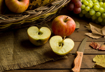 Fresh,ripe apples sliced on wooden table with wicker basket..Conceptual image of harvest season or Thanksgiving.