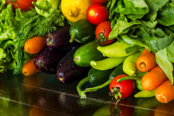Fresh,ripe vegetables on glass table with drops and reflection.