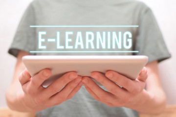 E-learning - man holding in hands digital tablet with white text on gray background. E-school and online education courses concept. 