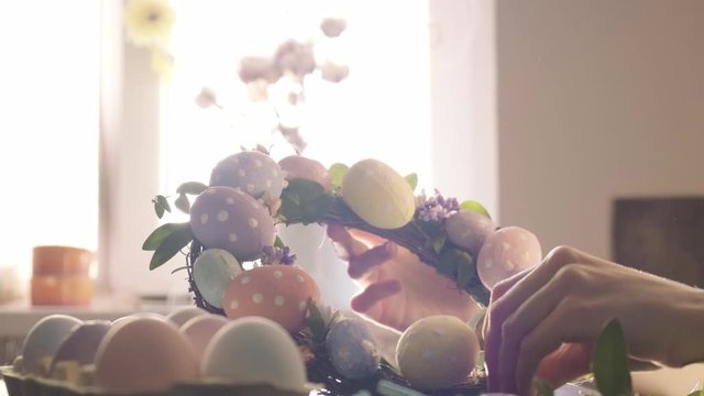 woman makes Easter decoration in the form of an Easter wreath with eggs and flowers