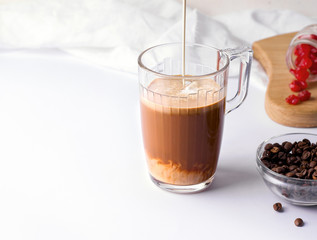 cup with coffee in which milk or cream is poured on a white background. copy space