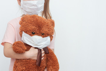 a child in a medical mask with a toy bear in hands, which is also masked. hygiene. security measures . health care concept. child protected from the virus.