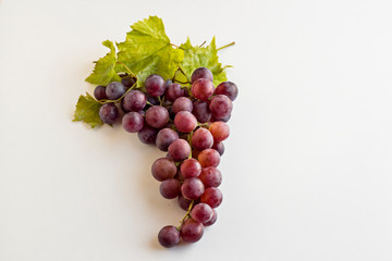A Bunch Of Grapes on the white surface with own leaves and copy space.